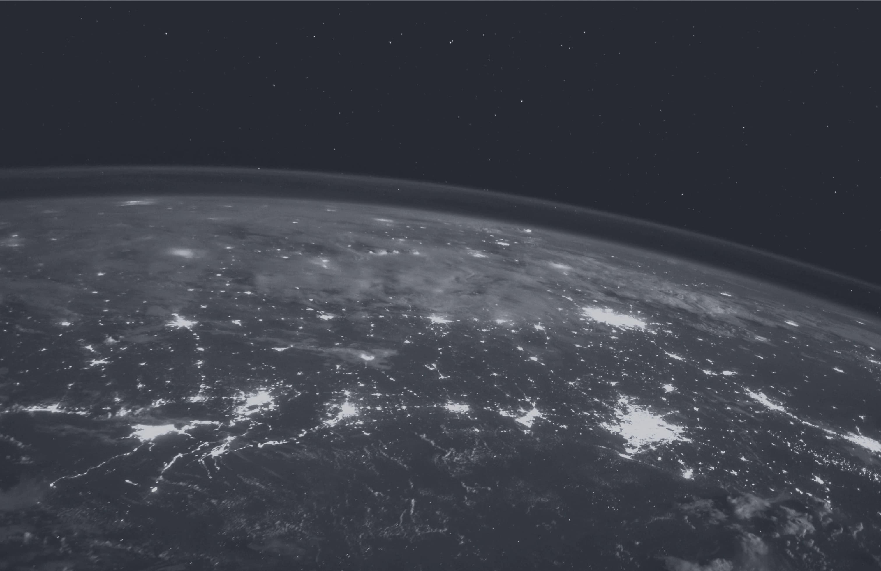 Satellite image of the world at night. Lights mark many cities, towns, and roadways.